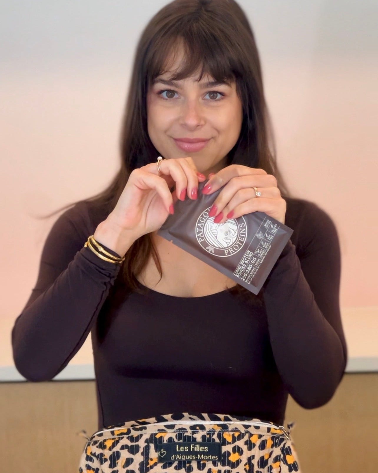 
                  
                    A woman with dark hair is holding a pouch of Andes Cocoa Patagonia Proteins, a chocolate vegan protein. The protein pouch is a single serving, perfect for travel! 
                  
                