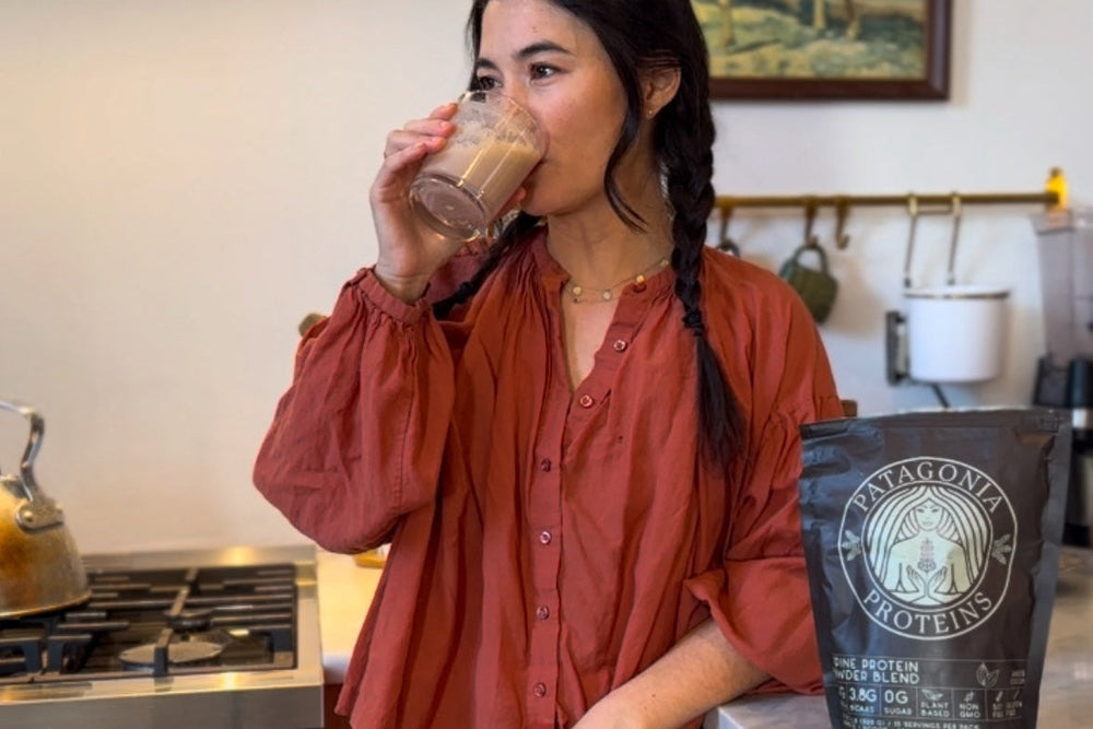 Woman drinking a beverage in a kitchen with a Patagonia Protein bag on the counter.