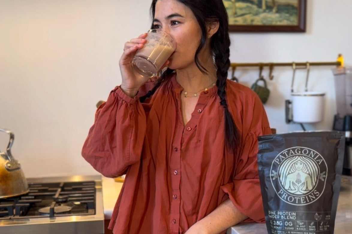 Woman drinking a beverage in a kitchen with a Patagonia Protein bag on the counter.
